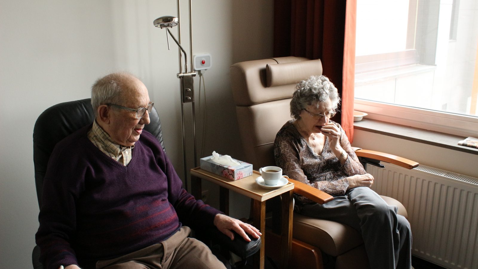 Elderly couple sitting in front of window