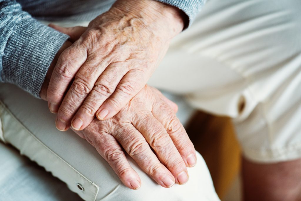 Elderly person's hands resting on their knee