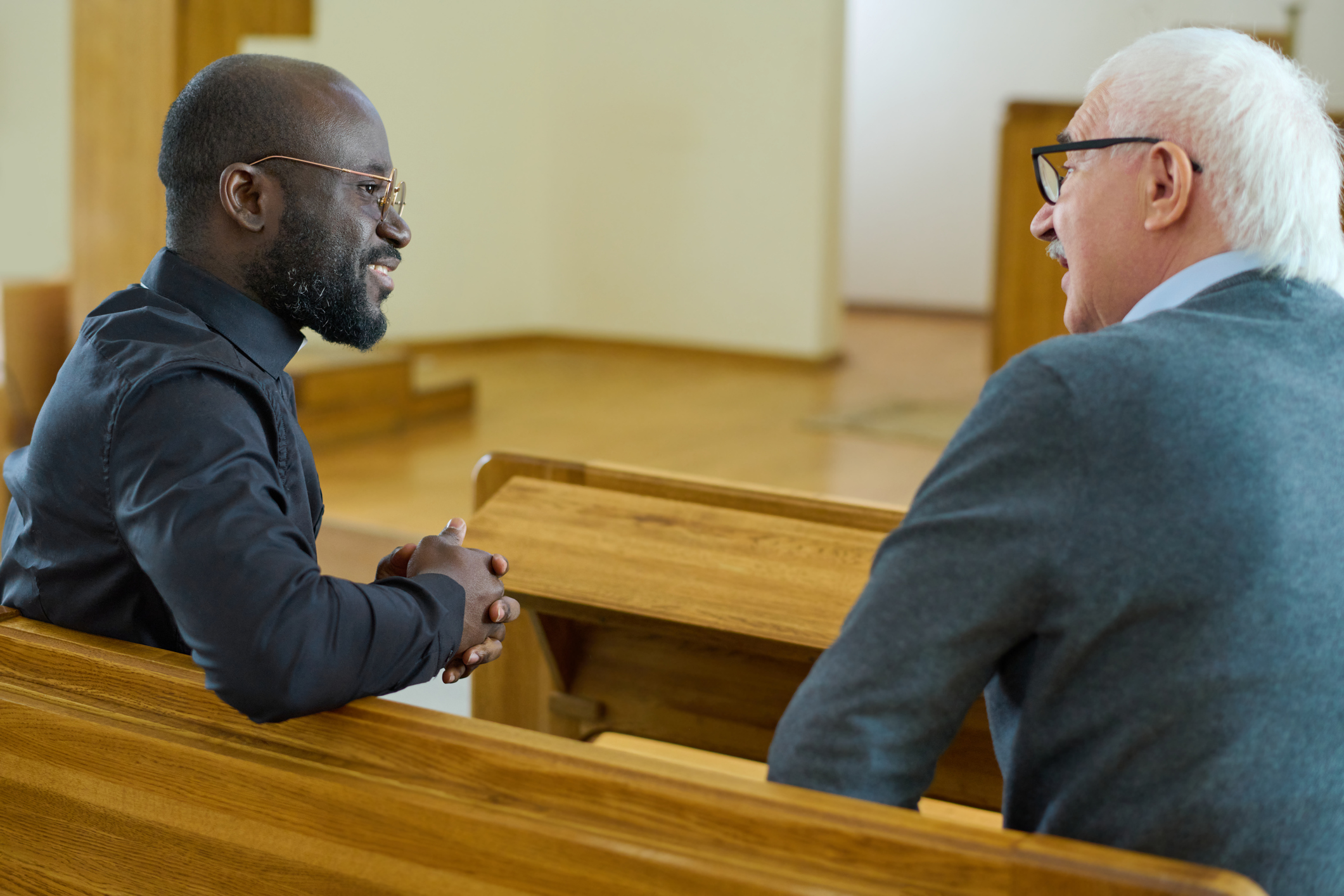 A young pastor speaks with an older adult.